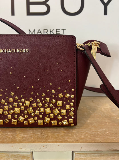 MICHAEL KORS. Bolso burdeos tachuelas doradas